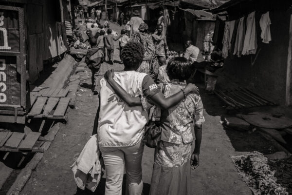Health teams and community get together in supporting each other. Here, a MSF staff walk with a local villager in Kibera, one of the largest slums in the world. Nairobi, Kenya.